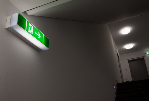 Green and white emergency lighting fitted on the corridor wall of the commercial premises